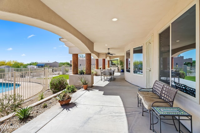 view of patio / terrace with fence, outdoor dining space, a ceiling fan, and a fenced in pool