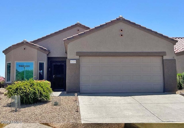 view of front facade featuring concrete driveway, a garage, a tile roof, and stucco siding