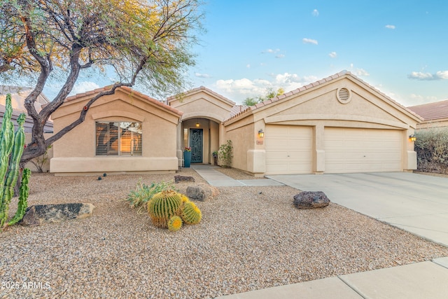 mediterranean / spanish home featuring stucco siding, driveway, a tile roof, and a garage