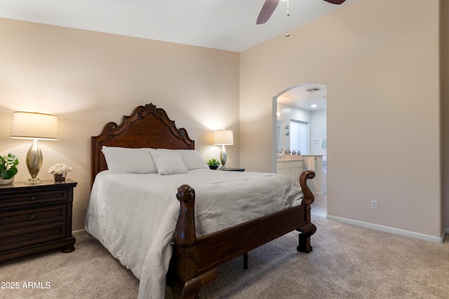 bedroom featuring ceiling fan, visible vents, light colored carpet, arched walkways, and connected bathroom