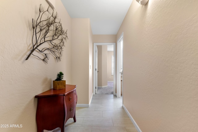 corridor featuring baseboards and a textured wall