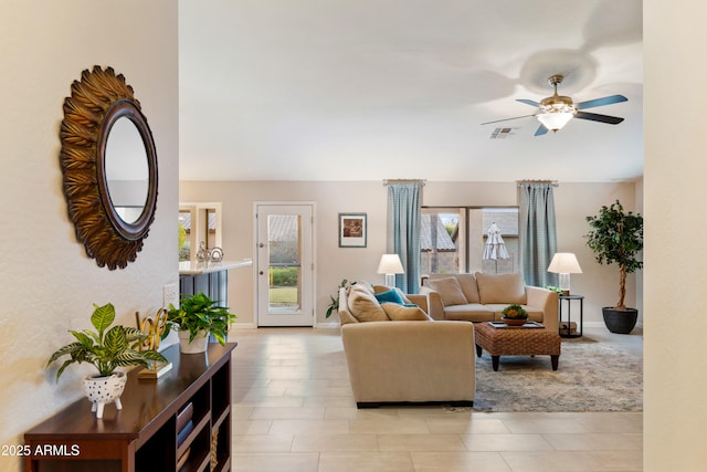 living area with visible vents, a ceiling fan, baseboards, and a wealth of natural light