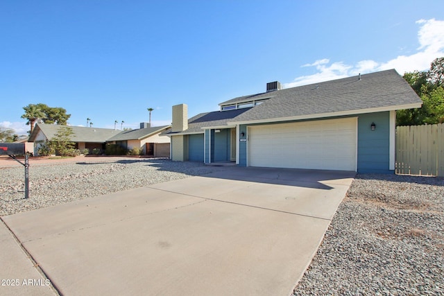 view of front of house with fence, roof with shingles, driveway, an attached garage, and a chimney