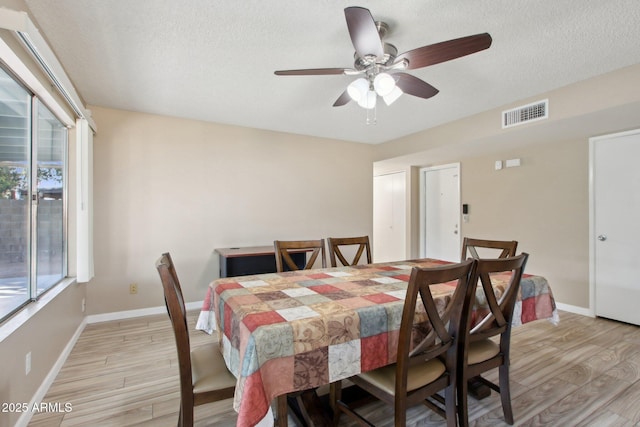 dining area with visible vents, baseboards, light wood-style flooring, and a ceiling fan