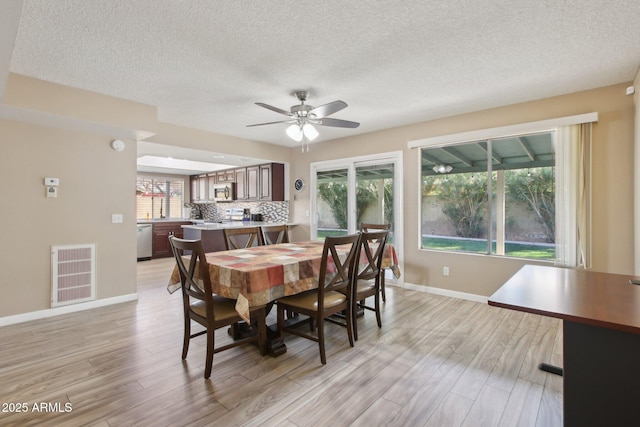 dining room featuring light wood finished floors, visible vents, and a wealth of natural light