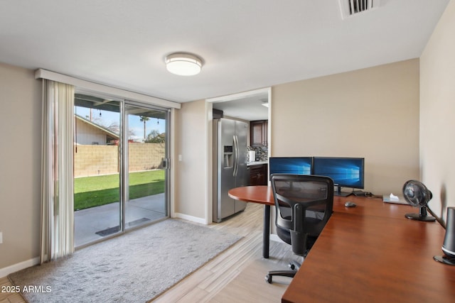 home office featuring a wall of windows, visible vents, baseboards, and light wood finished floors