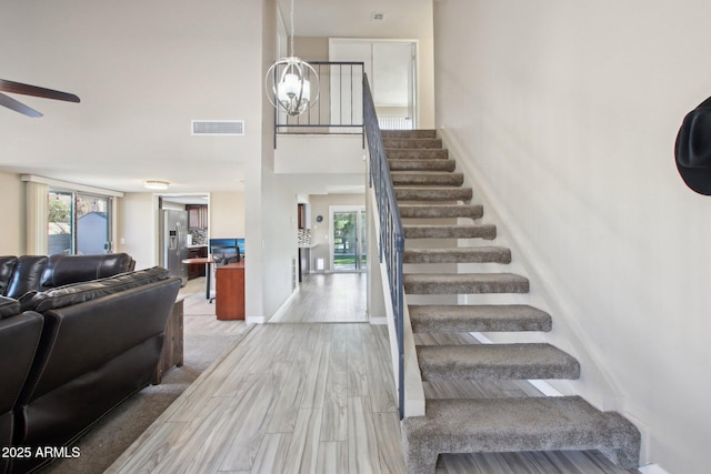 staircase featuring wood finished floors, visible vents, plenty of natural light, and ceiling fan