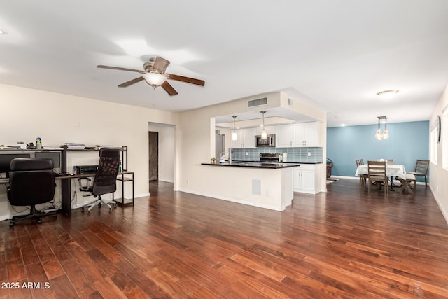 living area with dark wood-style flooring, ceiling fan with notable chandelier, baseboards, and visible vents