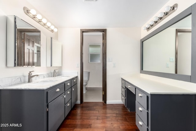 bathroom featuring toilet, double vanity, a sink, and hardwood / wood-style flooring