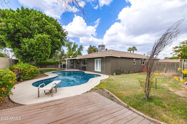 view of swimming pool featuring a fenced backyard, a wooden deck, a fenced in pool, and a lawn