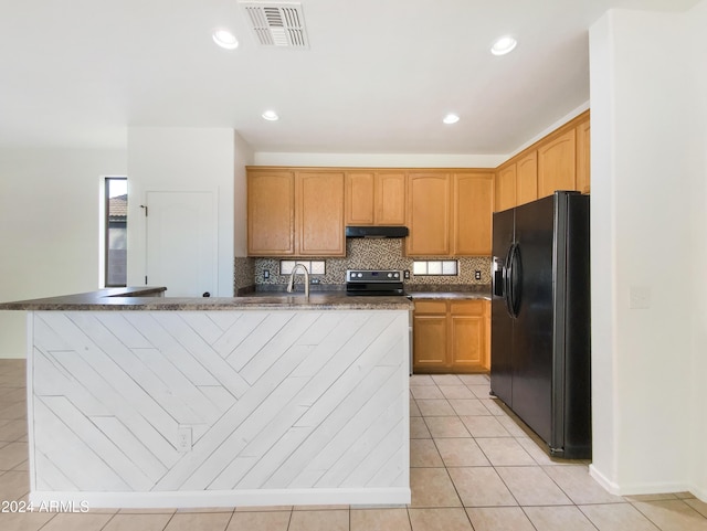 kitchen with tasteful backsplash, black fridge, stainless steel range with electric cooktop, and a kitchen island with sink