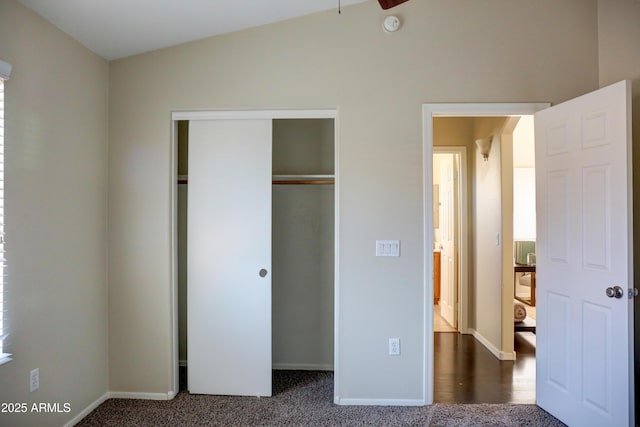 unfurnished bedroom with a closet, vaulted ceiling, and dark carpet