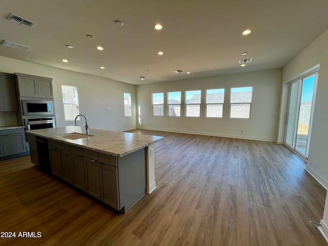 kitchen with light stone countertops, plenty of natural light, stainless steel appliances, and sink