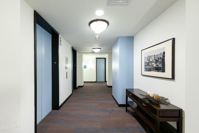 hall with dark wood-style flooring, baseboards, visible vents, and elevator