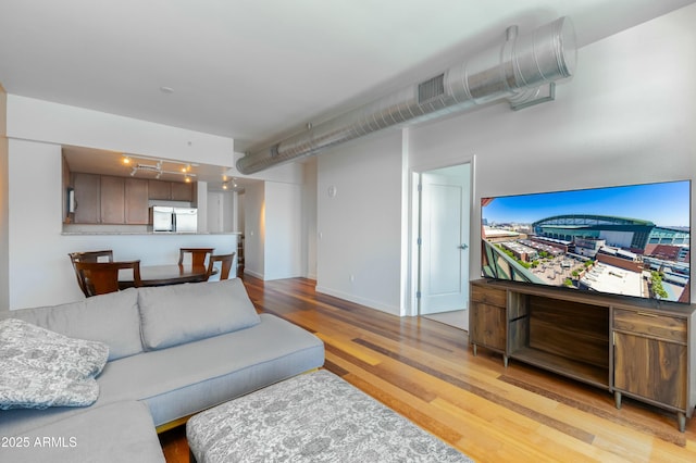 living area featuring light wood-type flooring, baseboards, and visible vents