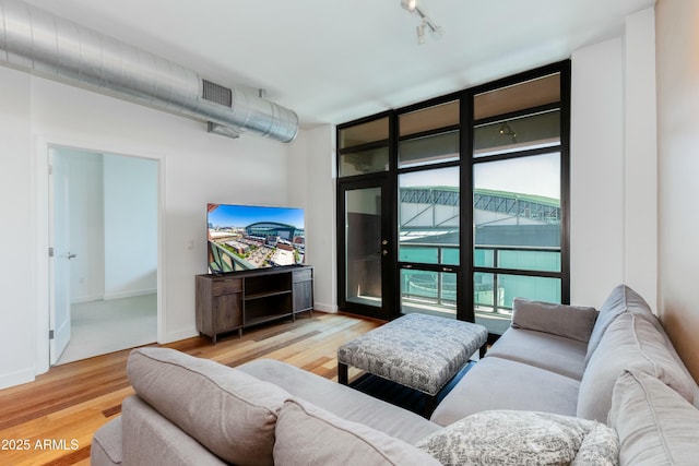 living area featuring track lighting, visible vents, baseboards, and wood finished floors
