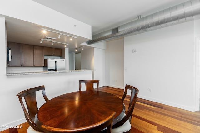 dining space with visible vents, baseboards, rail lighting, and wood finished floors