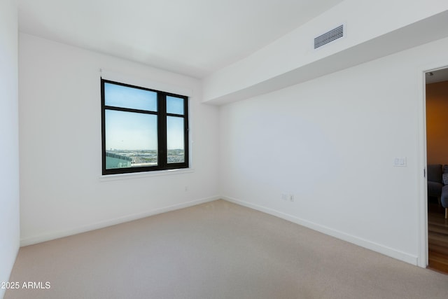 carpeted empty room featuring baseboards and visible vents