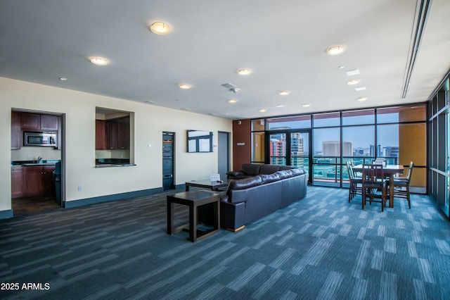 living area featuring recessed lighting, baseboards, dark carpet, and a wall of windows