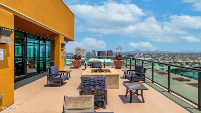 view of patio featuring a mountain view, a fire pit, a view of city, and a balcony