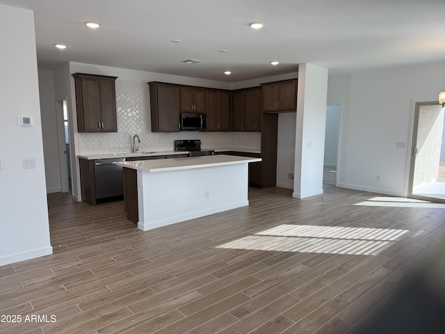 kitchen with dishwashing machine, a kitchen island, light hardwood / wood-style floors, sink, and black electric range