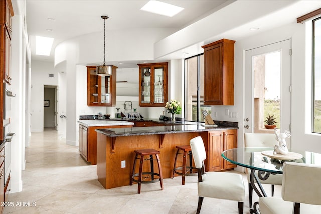 15816 E Eagle Crest Rd, Fountain Hills, AZ 85268 - kitchen featuring brown cabinetry, glass insert cabinets, a kitchen bar, a peninsula, and pendant lighting