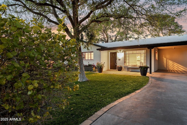 view of front of property featuring brick siding and a lawn