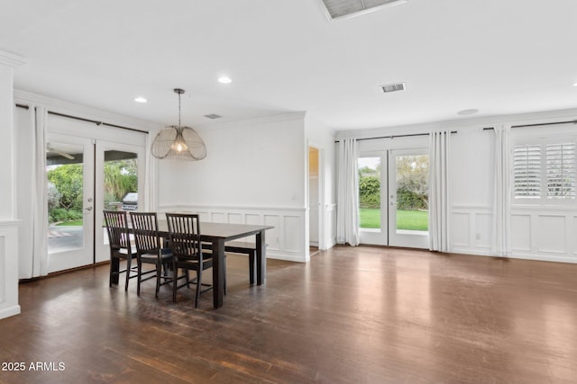 dining room with visible vents, a decorative wall, dark wood-type flooring, and ornamental molding