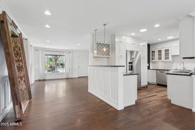 kitchen with dark countertops, appliances with stainless steel finishes, dark wood finished floors, and backsplash