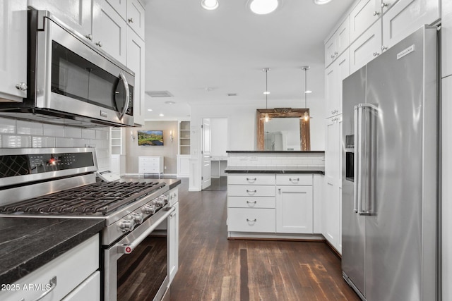 kitchen with dark wood-style floors, tasteful backsplash, appliances with stainless steel finishes, white cabinets, and a peninsula