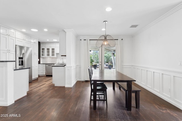 dining space with a wainscoted wall, dark wood-type flooring, crown molding, a decorative wall, and recessed lighting