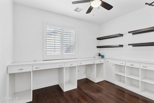 unfurnished office with built in study area, dark wood finished floors, visible vents, and ceiling fan