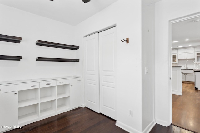 interior space with recessed lighting, dark wood-style flooring, a sink, and baseboards