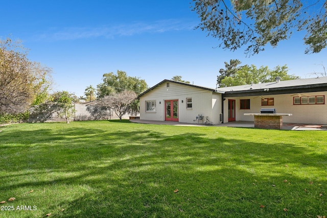 back of property featuring a patio area, a yard, and french doors