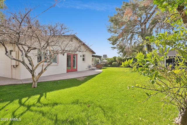 rear view of property featuring a yard, french doors, and a patio