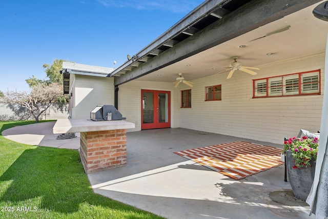 view of exterior entry with a patio area, a yard, a ceiling fan, and french doors