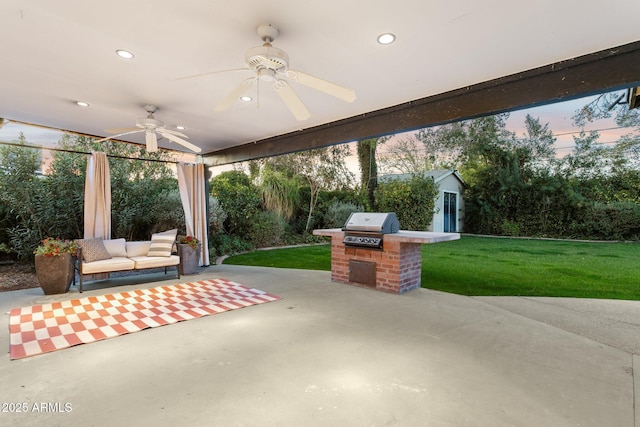 patio terrace at dusk with a yard, grilling area, a ceiling fan, and an outdoor structure