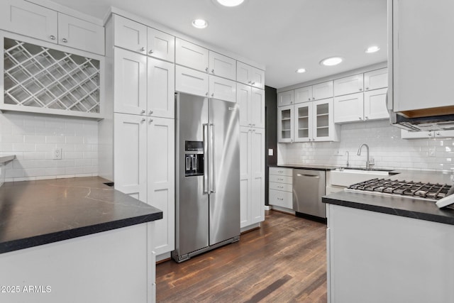 kitchen featuring appliances with stainless steel finishes, dark countertops, dark wood-style flooring, and white cabinetry
