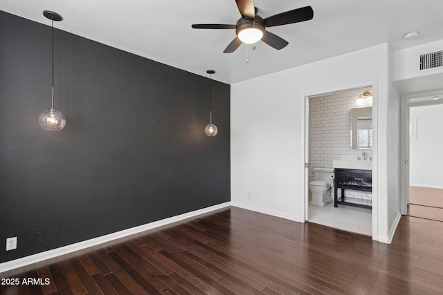 spare room with baseboards, wood finished floors, visible vents, and a ceiling fan