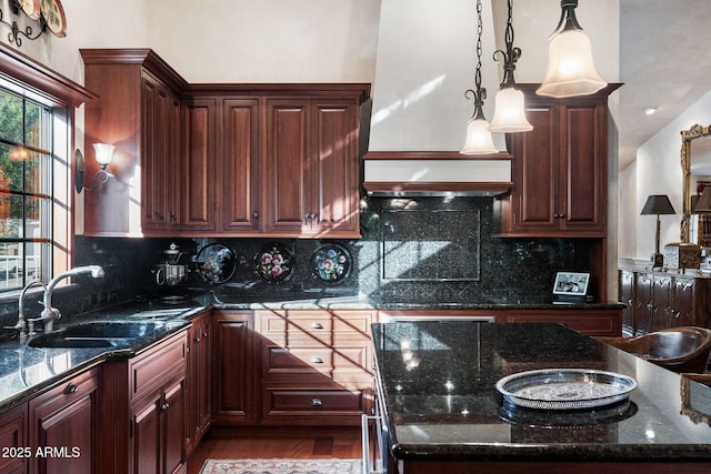 kitchen with sink, dark stone countertops, pendant lighting, and tasteful backsplash