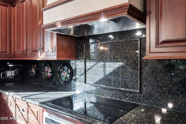 kitchen featuring dark stone countertops, wall oven, premium range hood, black electric cooktop, and decorative backsplash