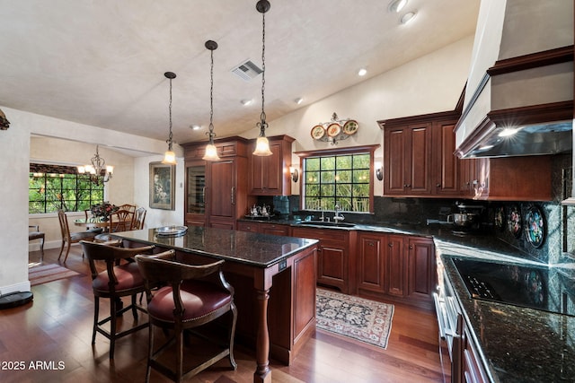 kitchen with a kitchen island, sink, decorative backsplash, and hanging light fixtures