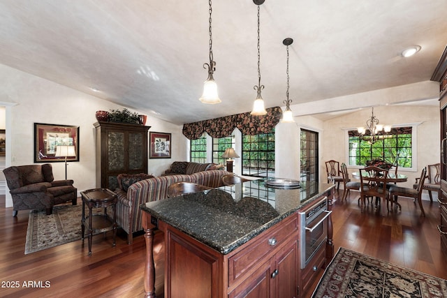 kitchen with oven, decorative light fixtures, vaulted ceiling, and dark stone countertops