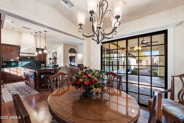 dining area featuring ceiling fan with notable chandelier, vaulted ceiling, and dark hardwood / wood-style floors