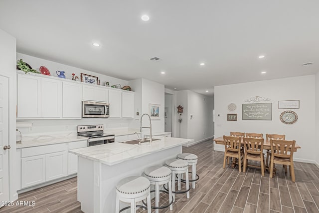 2923 W Shanley Ave, Apache Junction, AZ 85120 - kitchen with visible vents, a center island with sink, wood finish floors, a sink, and stainless steel appliances