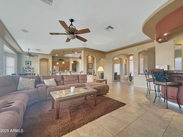 living room with ceiling fan, ornamental molding, and light tile patterned floors