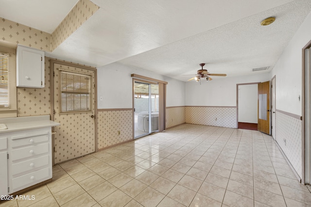 interior space featuring ceiling fan, a textured ceiling, and light tile patterned flooring