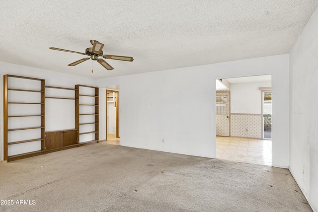 spare room with ceiling fan, light colored carpet, and a textured ceiling