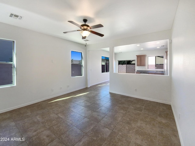 unfurnished living room with dark tile patterned flooring and ceiling fan