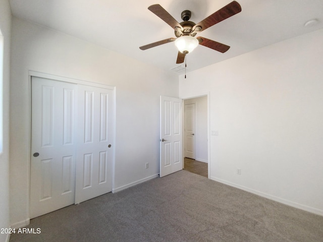 unfurnished bedroom with ceiling fan, dark carpet, and a closet